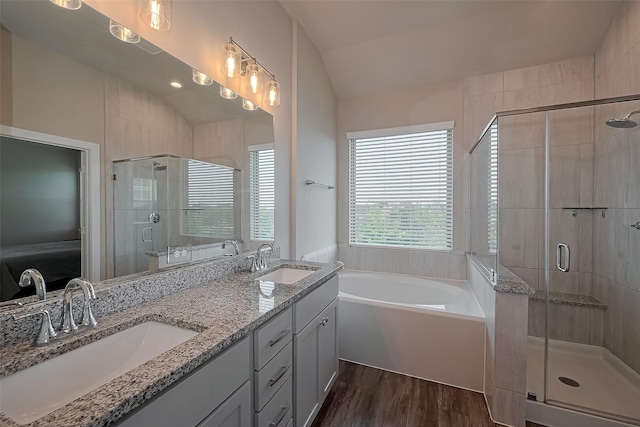 bathroom with vaulted ceiling, a stall shower, wood finished floors, and a sink