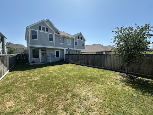 back of house featuring central air condition unit, a yard, and a fenced backyard