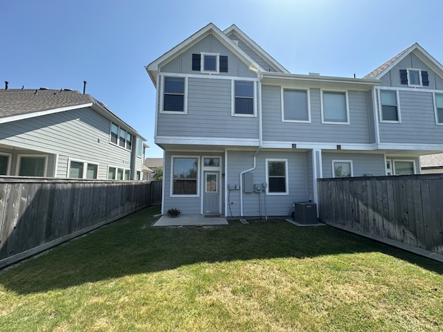 back of house featuring central AC unit, a fenced backyard, and a lawn