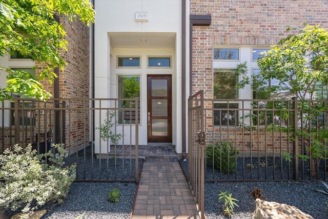 entrance to property featuring brick siding, stucco siding, and fence