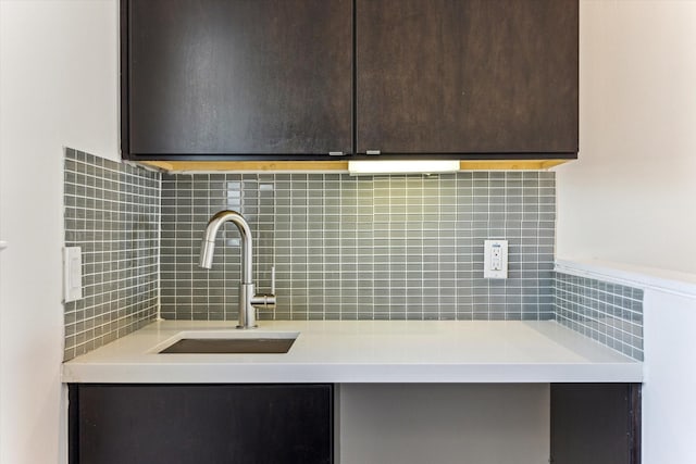 kitchen featuring backsplash, light countertops, dark brown cabinets, and a sink
