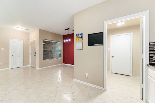 empty room featuring light tile patterned flooring, baseboards, and visible vents