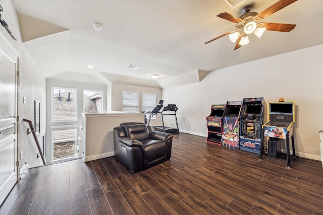 sitting room featuring wood finished floors, lofted ceiling, baseboards, ceiling fan, and an upstairs landing