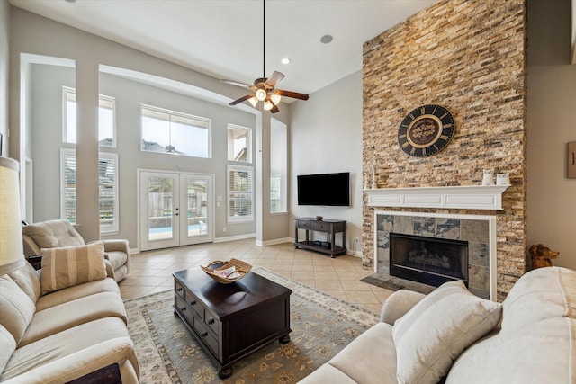 living room featuring a ceiling fan, french doors, a towering ceiling, tile patterned flooring, and baseboards