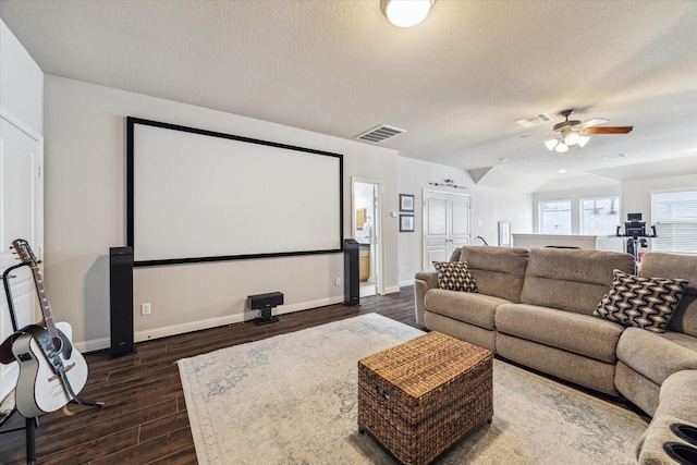 home theater room featuring dark wood-style flooring, a textured ceiling, a ceiling fan, vaulted ceiling, and visible vents