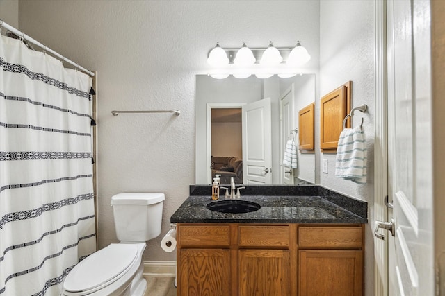 bathroom featuring vanity, a textured wall, a shower with shower curtain, and toilet