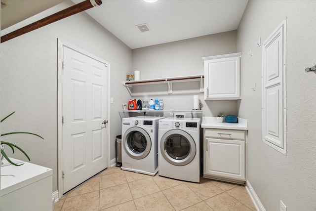 washroom featuring light tile patterned floors, separate washer and dryer, cabinet space, and visible vents