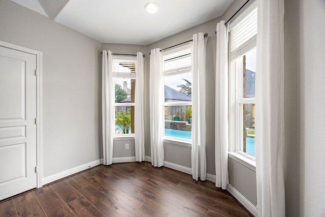 doorway to outside featuring dark wood-style flooring, baseboards, and a healthy amount of sunlight