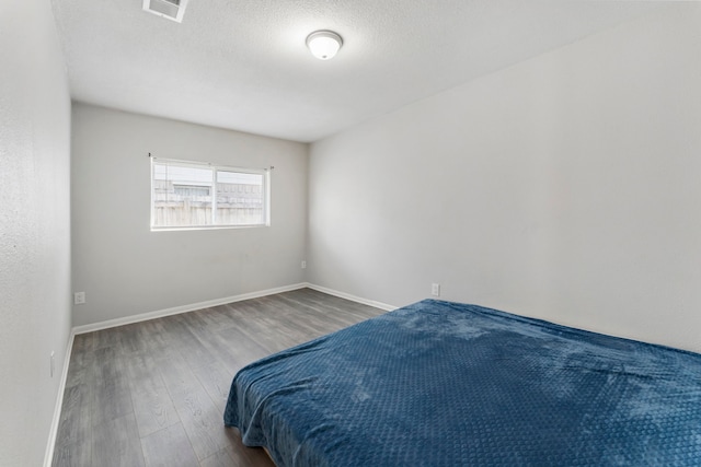 19822 Brightstone Dr, Humble, TX 77338 - bedroom featuring visible vents, a textured ceiling, baseboards, and wood finished floors