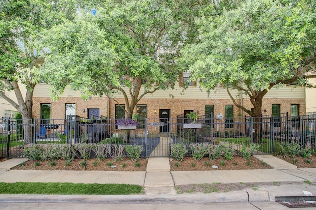 multi unit property with brick siding, a gate, and a fenced front yard