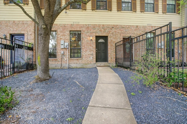 entrance to property with brick siding and fence
