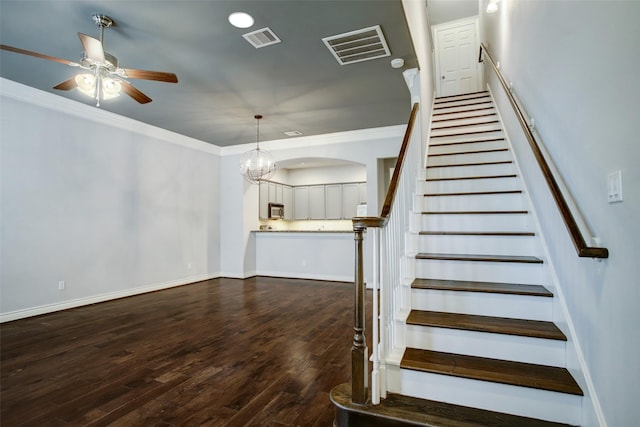 stairs with visible vents, ornamental molding, and ceiling fan with notable chandelier