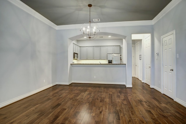 kitchen with dark wood-type flooring, crown molding, a notable chandelier, and stainless steel appliances