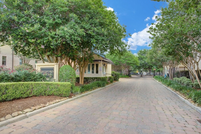 view of street featuring a gate, a gated entry, and curbs