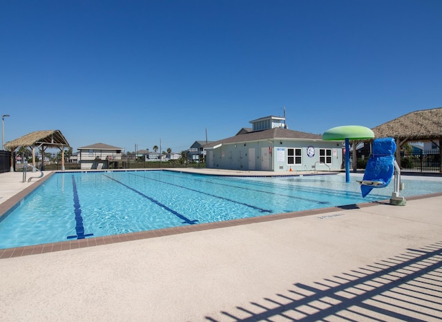 community pool with fence, a gazebo, and a patio area