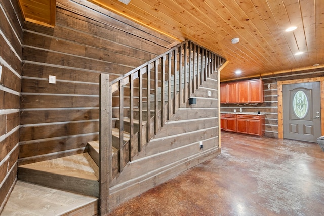 stairway with concrete floors, wooden walls, and recessed lighting