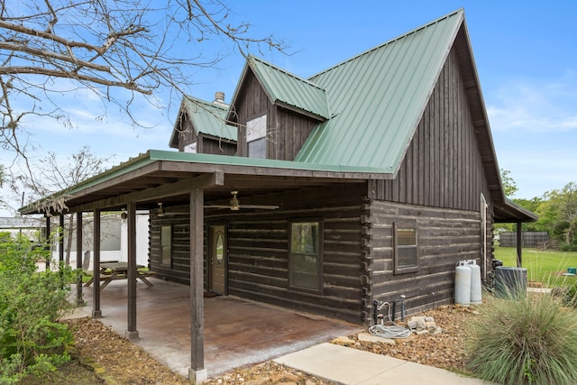 view of home's exterior with central air condition unit, log siding, a patio area, and metal roof