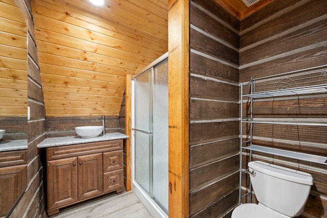 bathroom featuring vanity, a stall shower, wooden walls, toilet, and wood finished floors