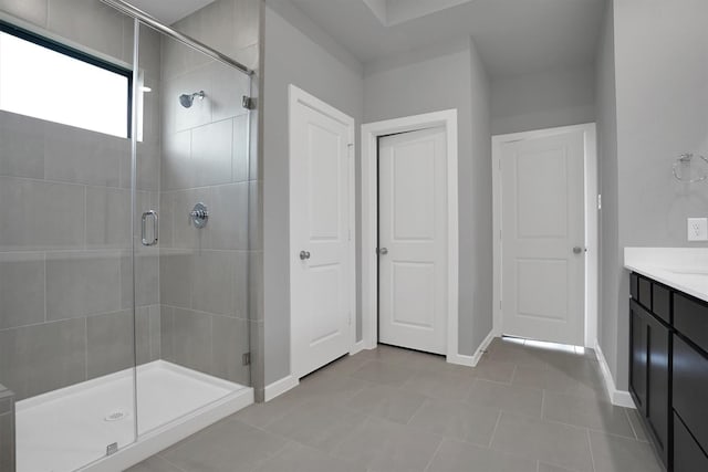bathroom featuring tile patterned floors, baseboards, vanity, and a stall shower