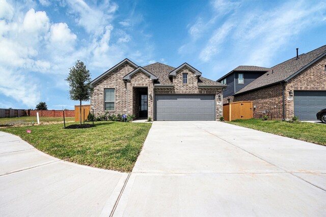 view of front of house with concrete driveway, fence, brick siding, an attached garage, and a front yard