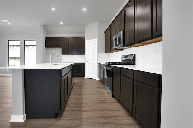 kitchen featuring decorative backsplash, stainless steel appliances, wood finished floors, and a sink