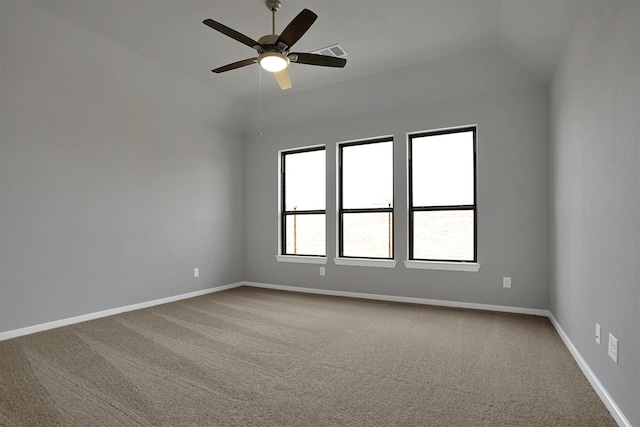 carpeted spare room featuring baseboards, a ceiling fan, visible vents, and vaulted ceiling