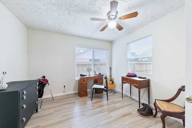 office area featuring baseboards, light wood-style flooring, a textured ceiling, and a ceiling fan