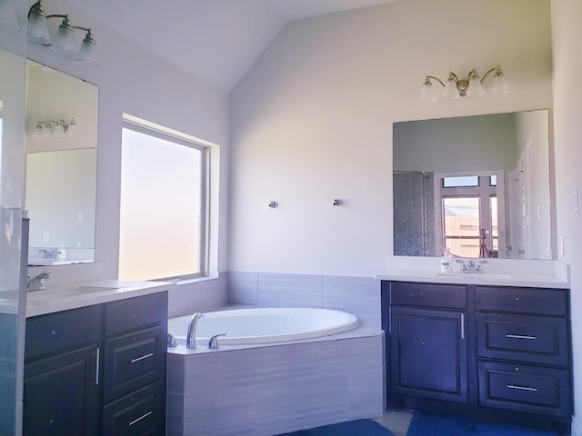 full bath with a sink, vaulted ceiling, a bath, and two vanities
