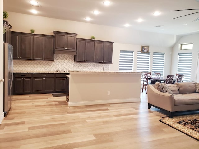 kitchen featuring dark brown cabinetry, stainless steel fridge with ice dispenser, light wood finished floors, backsplash, and vaulted ceiling