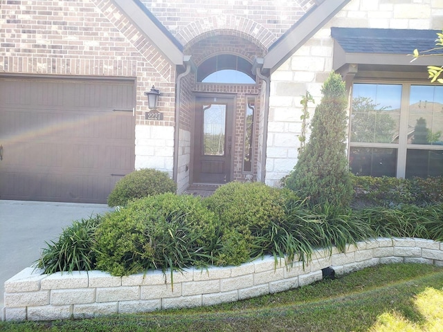 doorway to property with brick siding, a garage, and stone siding