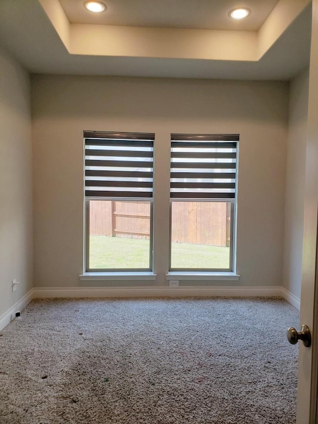 carpeted empty room featuring baseboards, recessed lighting, a tray ceiling, and a healthy amount of sunlight