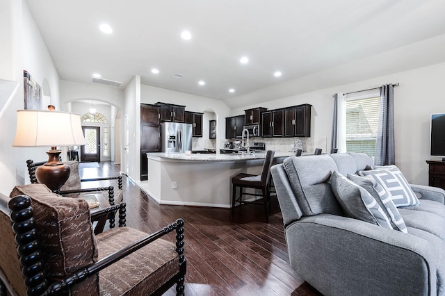 living room featuring plenty of natural light, arched walkways, dark wood-style flooring, and visible vents