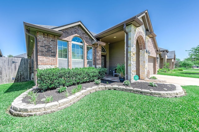 view of front of property featuring brick siding, a front yard, fence, and stone siding