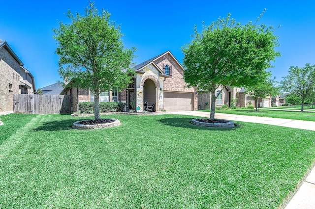 view of property hidden behind natural elements with fence, a front yard, stone siding, concrete driveway, and an attached garage