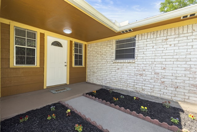 doorway to property featuring brick siding