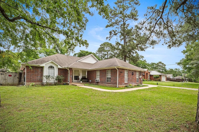 ranch-style home with fence, roof with shingles, a front lawn, and brick siding