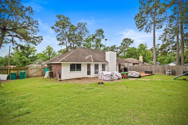 back of property featuring a yard, a gate, a fenced backyard, and a chimney