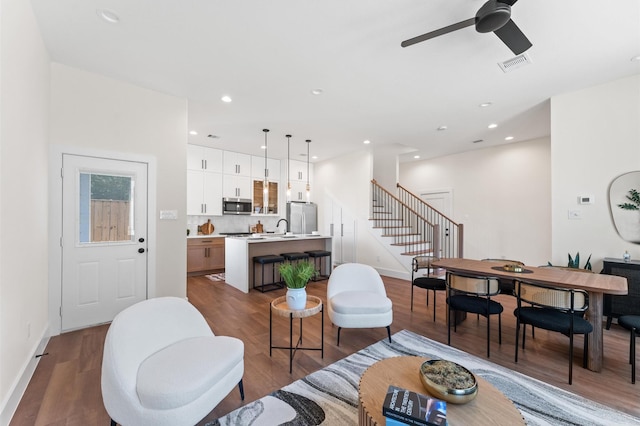 living room with visible vents, stairway, and wood finished floors