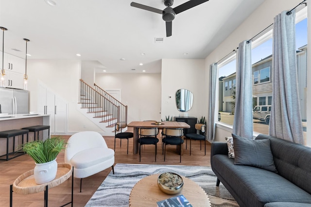 living room featuring visible vents, light wood-type flooring, a ceiling fan, recessed lighting, and stairs