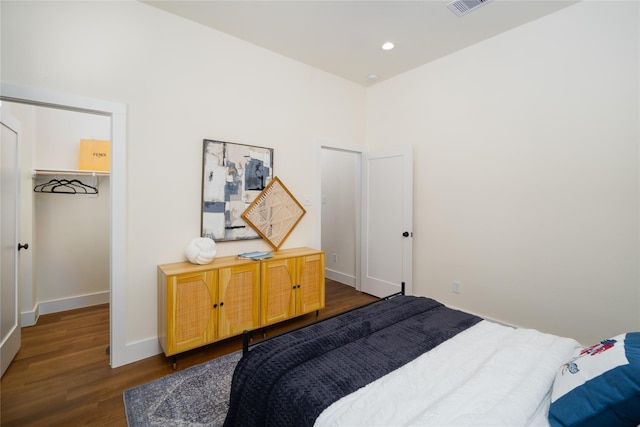 bedroom featuring dark wood finished floors, a closet, recessed lighting, a walk in closet, and baseboards