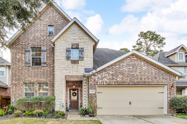 view of front of house featuring brick siding, an attached garage, stone siding, and driveway