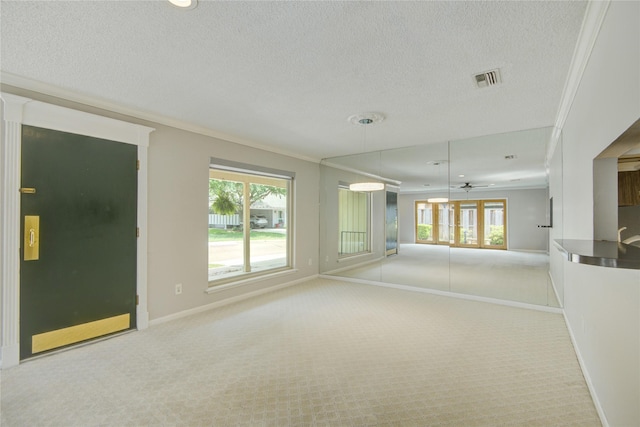 unfurnished living room with carpet floors, a textured ceiling, crown molding, and baseboards