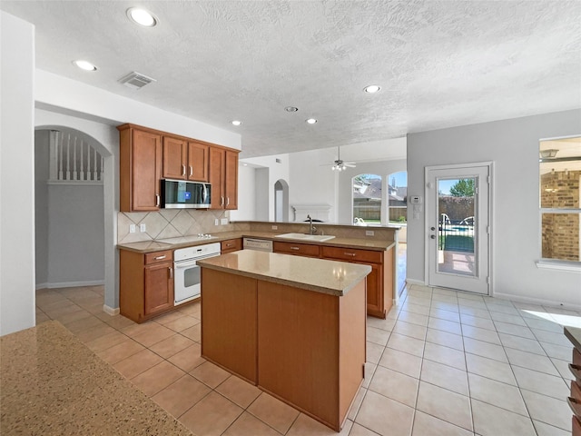 7206 Fiesta Flower, Katy, TX 77494 - kitchen featuring tasteful backsplash, white appliances, light tile patterned floors, a peninsula, and arched walkways