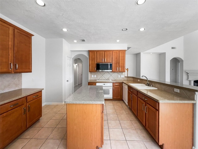 7206 Fiesta Flower, Katy, TX 77494 - kitchen featuring white appliances, arched walkways, a center island, a sink, and decorative backsplash