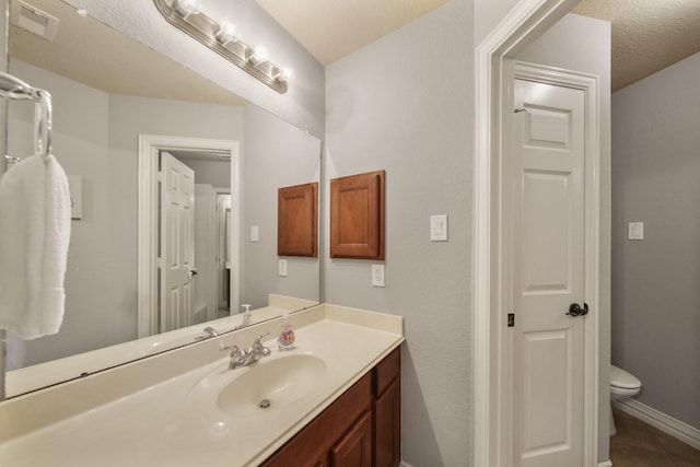 bathroom featuring toilet, vanity, baseboards, and tile patterned flooring