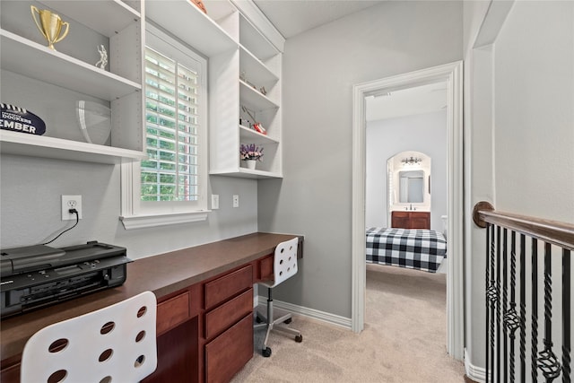 office space with built in desk, light colored carpet, and baseboards