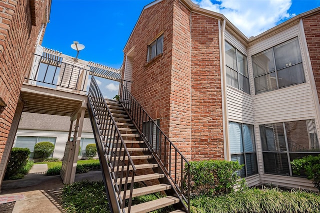 view of home's exterior with stairs and brick siding