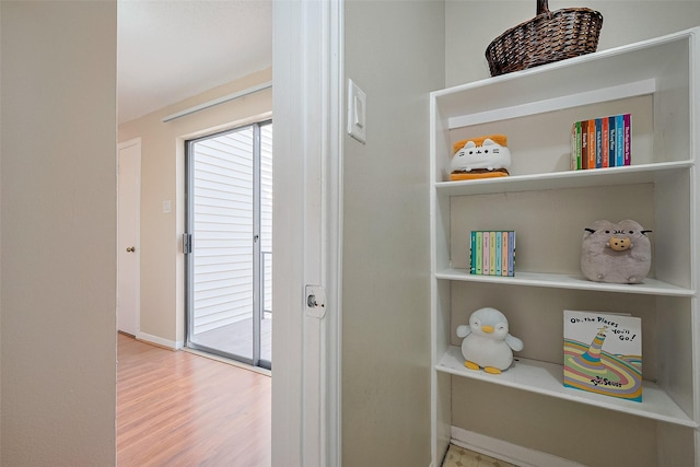 hallway featuring wood finished floors, a healthy amount of sunlight, and baseboards