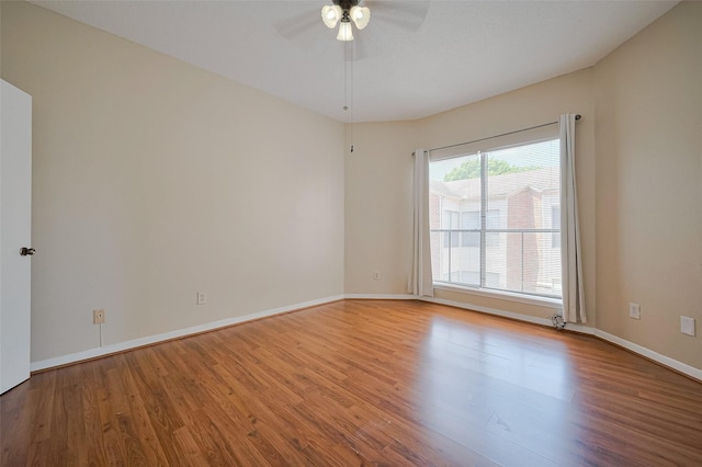 empty room with baseboards, wood finished floors, and a ceiling fan