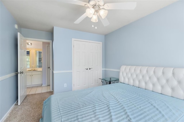 bedroom featuring baseboards, a closet, ceiling fan, light colored carpet, and a sink